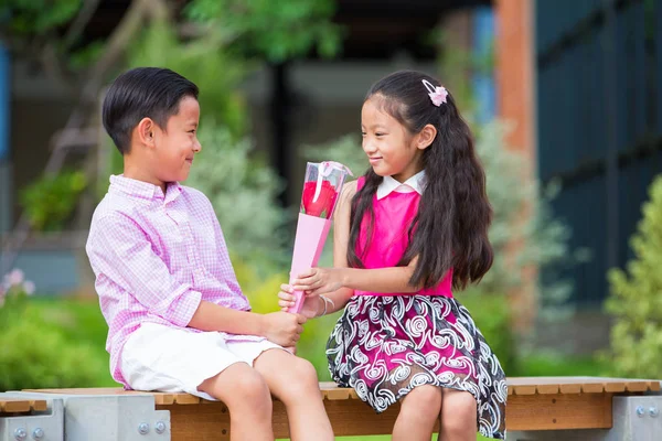 Malé asijské boy dát růžový květ pro malou holčičku v zahradě, Val — Stock fotografie