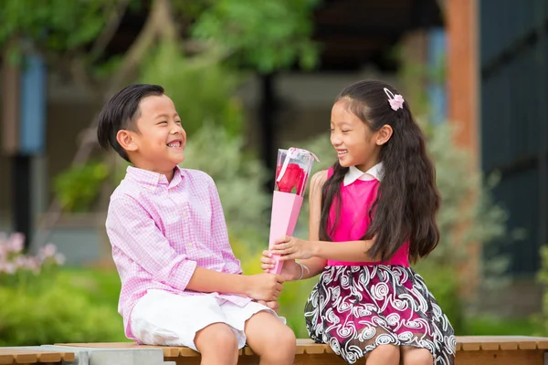 Little shy boy give rose flower for little girl in garden, Valen — Stock Photo, Image