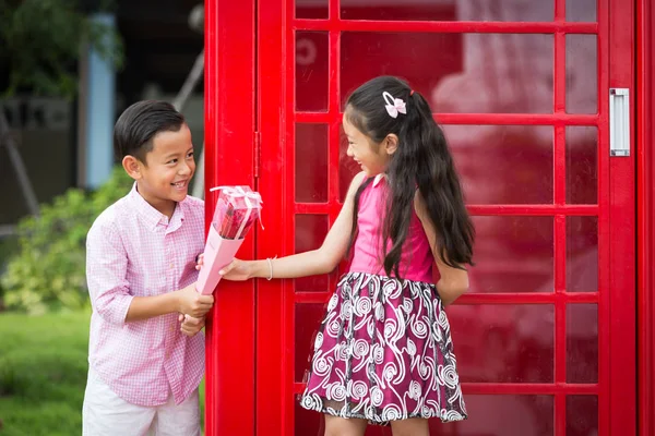 Kleine asiatische Junge geben Rose Blume für kleines Mädchen im Garten, val — Stockfoto