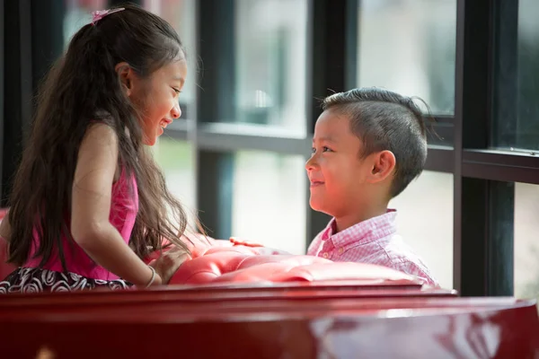 Piccolo asiatico ragazzo e ragazza godere giocare su rosso divano valentino o — Foto Stock