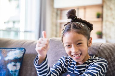 Küçük Asyalı kız gülümseyerek ve Asansör el başparmak parmak ile