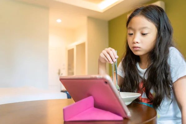 Pequeña chica asiática viendo contenido de Internet en la tableta de ordenador d — Foto de Stock