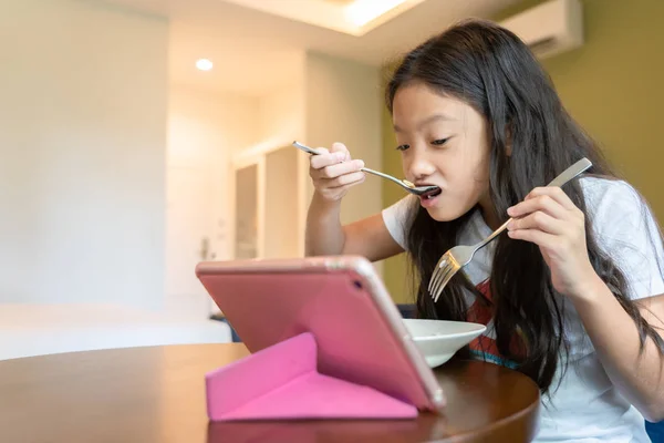 Little Asian girl watching internet content in computer tablet d — Stock Photo, Image