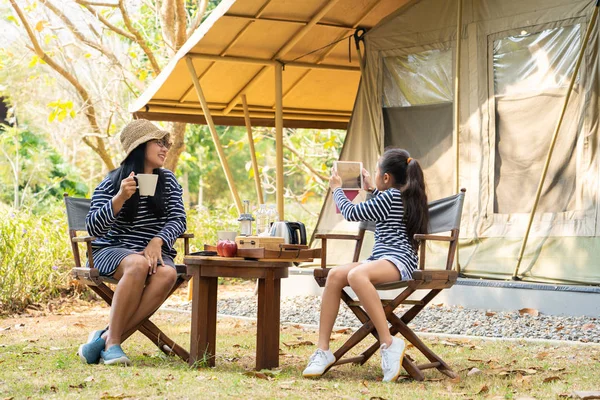 Happy asian family enjoy camping outdoors, Mom and daughter sitt