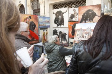 Arles France 31. Mart 2013. Feria Arles Paskalyası. Amfitiyatronun duvarlarının önündeki sokak ressamı. Turistlerden önce, şehrin boğa, torreador ve eski binalarının görüntüleri resmedilir.. 