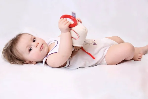 Uma Criança Pequena Jaz Chão Com Brinquedo Fundo Branco Fotografia — Fotografia de Stock