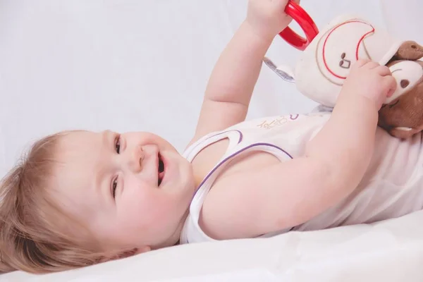 Uma Criança Pequena Jaz Chão Com Brinquedo Fundo Branco Fotografia — Fotografia de Stock