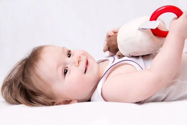 Uma Criança Pequena Jaz Chão Com Brinquedo Fundo Branco Fotografia — Fotografia de Stock