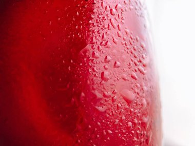 Kırmızı bir içeceğin cam şişesinin üzerindeki damlaların yakın plan fotoğrafı. İçkilerin fotoğrafı. Reklam kavramı.