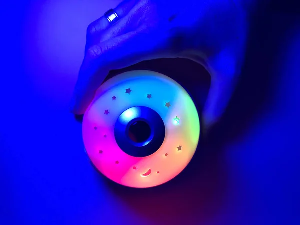 Lámpara de noche brillante en diferentes colores de RGB en una mano femenina . — Foto de Stock