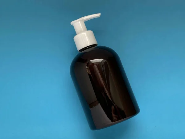 Mavi arka planda sabun dağıtıcısı. Hijyen ve bakım kavramı.