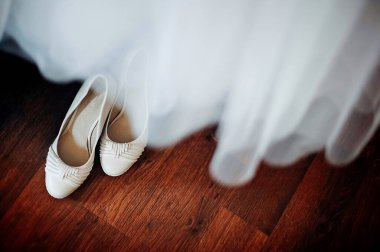 Gelinin düğün ayakkabıları, gelinliğin arkasında. Düğün konsepti.