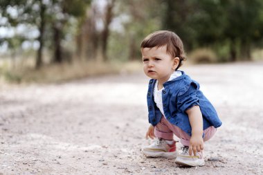 Mutlu anne kızıyla birlikte doğada yürürken kameraya bakıyor.