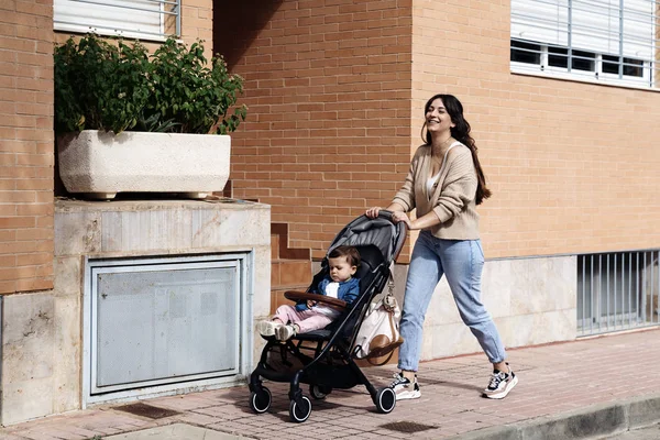 Щаслива сім'я гуляє з дитячим візком на природі Щаслива сім'я гуляє на вулиці з дитячим візком — стокове фото