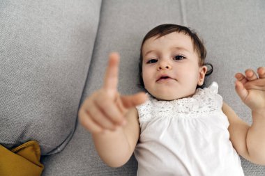 Kanepede uzanmış kameraya bakan küçük bir kız..