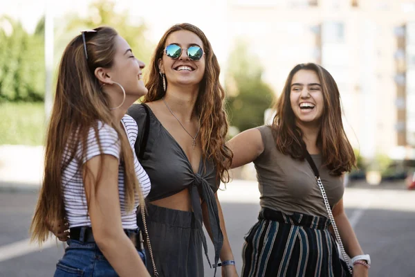 Three pretty female friends walking in the street looking at them and smiling — ストック写真