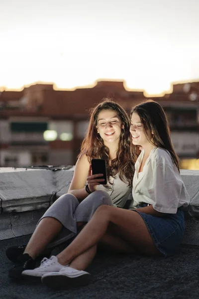Νεαρό θηλυκό ζευγάρι που χρησιμοποιεί smartphone σε ταράτσα — Φωτογραφία Αρχείου