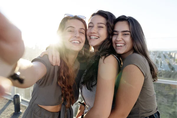 Three female friends taking a selfie on a rooftop