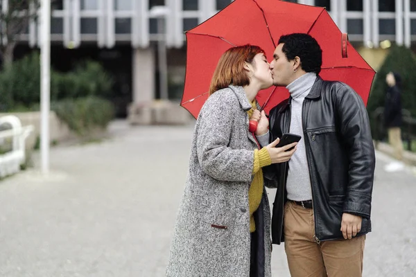 Casal feliz olhando para si mesmos e sorrindo enquanto chove — Fotografia de Stock