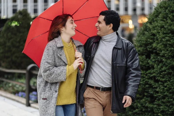 Casal feliz olhando para si mesmos e sorrindo enquanto chove — Fotografia de Stock