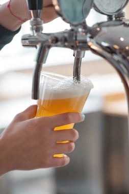 plastik bardak bira bira musluk ile güzel köpük yakın çekim kadın barmen olarak üzerinden akan arka plan bulanık eller 