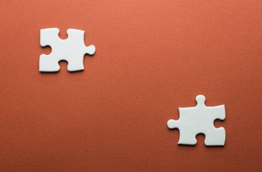 Turuncu bir arkaplanda iki ayrı yapboz parçası