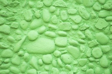 Arkaplan için çok belirgin bir dokusu olan açık yeşil boyalı küçük taşlardan oluşan bir duvar.