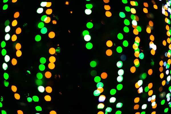 Background of green and orange glitter lights. Defocused