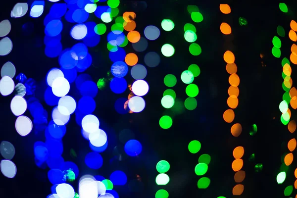 Background of green, blue and orange glitter lights. Defocused