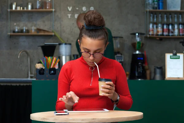 Menina adolescente com um tablet senta-se em um café . — Fotografia de Stock