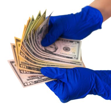 Ellerinde bir tomar dolar tutan tıbbi eldivenli eller. Para, kirli para, ödenmiş ilaç, tedavi ücretleri, rüşvetler, yasadışı ameliyat.