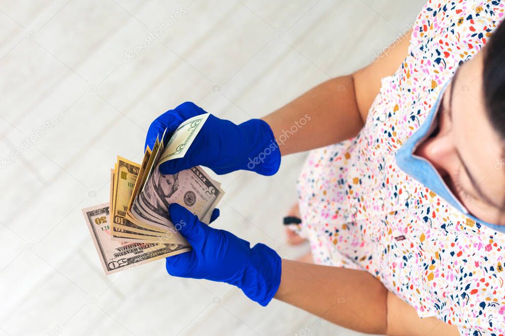 Girl holds in hands in medical gloved pack of dollars. The concept of infection on money, dirty money, paid medicine, treatment fees, bribes, illegal surgery.