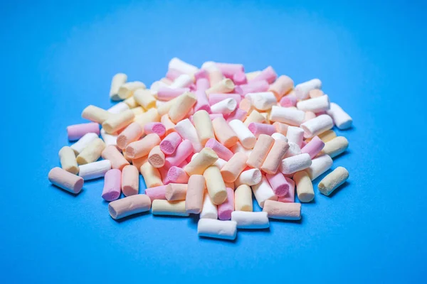 A slide of colored marshmallows on a blue background. Confectionery sweet background