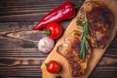 Köy ahşap bir masada ızgara domuz eti ve sebze. Kemiklerde ızgara et, baharat, sarımsak, biber, domates ve biberiye. Restoran menüsü. Yukarıdan görünüm