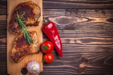 Köy ahşap bir masada ızgara domuz eti ve sebze. Kemiklerde ızgara et, baharat, sarımsak, biber, domates ve biberiye. Restoran menüsü. Yukarıdan görünüm