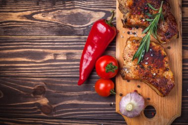 Köy ahşap bir masada ızgara domuz eti ve sebze. Kemiklerde ızgara et, baharat, sarımsak, biber, domates ve biberiye. Restoran menüsü. Yukarıdan görünüm