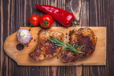 Köy ahşap bir masada ızgara domuz eti ve sebze. Kemiklerde ızgara et, baharat, sarımsak, biber, domates ve biberiye. Restoran menüsü. Yukarıdan görünüm