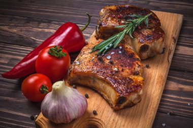 Köy ahşap bir masada ızgara domuz eti ve sebze. Kemiklerde ızgara et, baharat, sarımsak, biber, domates ve biberiye. Restoran menüsü. Yukarıdan görünüm