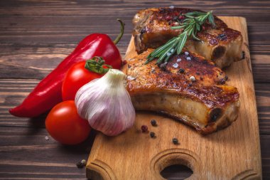 Köy ahşap bir masada ızgara domuz eti ve sebze. Kemiklerde ızgara et, baharat, sarımsak, biber, domates ve biberiye. Restoran menüsü