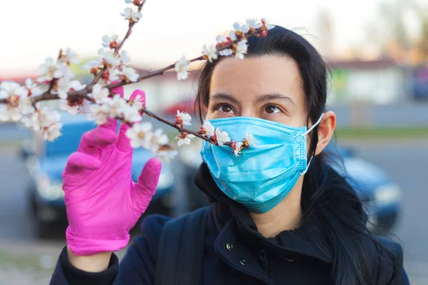 Dziewczyna Ochronnej Masce Medycznej Gumowych Rękawiczkach Wiosną Ulicy Patrzy Kwitnące — Zdjęcie stockowe