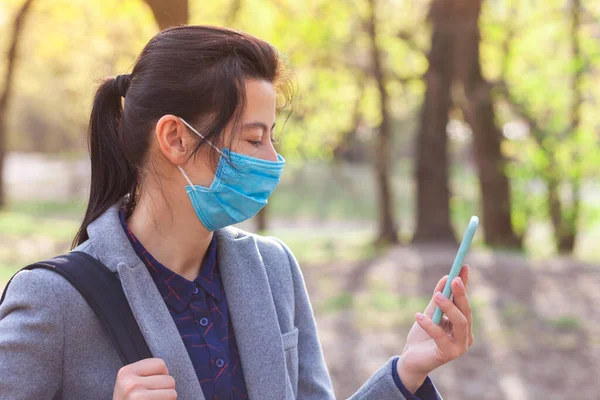 Dziewczyna Używa Smartfona Nosi Ochronną Maskę Medyczną Powodu Zakaźnych Chorób — Zdjęcie stockowe