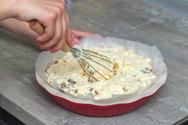 Çiğ süzme peynir güveç hamuru, yuvarlak seramik fırın kabında, kadın elleri hamuru yoğurur..