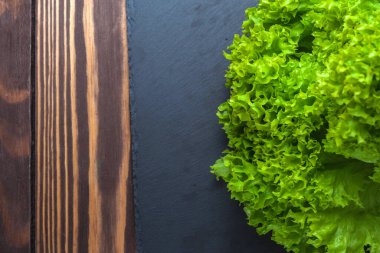 Salatalı arka plan. Tahta bir masanın üstünde, siyah bir levhada duran bir sürü yeşil marul. Taze meyve suyu.