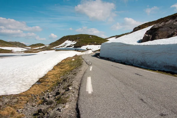 Driving in Norway in summer with snow walls along the road on a beautiful sunny day