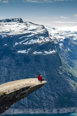 Bir uçurumun üzerinde bir göl, Trolltunga, Norveç kavramı macera, özgürlük ve aşırı yaşam tarzı oturan uzun yürüyüşe çıkan kimse Çift