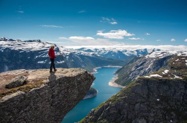 Uzun yürüyüşe çıkan kimse kadın uçurumdan üzerinde duran bir göl, Trolltunga, Norveç