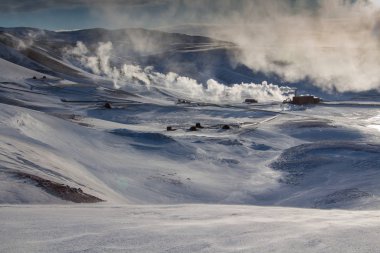 Buhar, buhar, mavi gökyüzü ve güneşli dağ manzarası Krafla jeotermal enerji santrali, Kuzey İzlanda. Huysuz kış doğası.