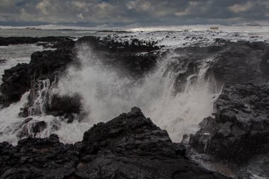 Powerful waves hit the cliff sprinkling water drops all over. Reykjanes peninsula, Iceland