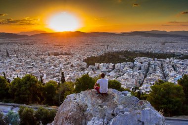 Atina 'da inanılmaz bir gün batımı, Lycabettus tepesinden manzara. Gezgin manzaranın tadını çıkarıyor