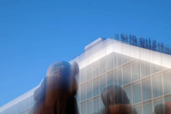 Güneşli bir günde ofis binasına karşı insanların görüntüsü bulanık.